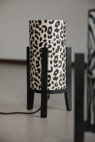 Eruca 34cm Leopard bordlampe Fra Markslöjd - Lampefoten i svart tre er kombinert med en sylindrisk tekstilskjerm i off-white og brunt leopardm&oslash;nster, noe som gir lampen en trendy og personlig karakter.