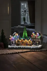 Mekanisk Juledekorasjon Med Julemarked 24cm Flerfarget Fra Konstsmide - Med 28 varmhvite LED-lys, overbygde hus, fargerike markedsboder og et digert juletre i sentrum, sprer det b&aring;de lys og musikk.
