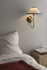 Iris 32cm Messing/kremhvit vegglampe Fra Globen Lighting - Den mykt buede armen er kombinert med en kremhvit tekstilskjerm som skaper et varmt og klassisk uttrykk.