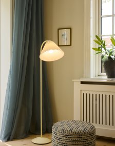 Medina Kremhvit gulvlampe Fra Halo Design - Den kremhvite metallrammen kompletteres av en vakker plissert tekstilskjerm i matchende skjerm og dekorative detaljer i messing.