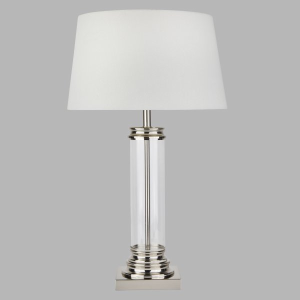 Pedestal 50cm Sølv bordlampe Fra Searchlight - Med sin stilige ramme i gjennomsiktig glass og polert metall, sammen med en tidløs hvit lampeskjerm, passer den perfekt inn i både moderne og tradisjonelle miljøer.
