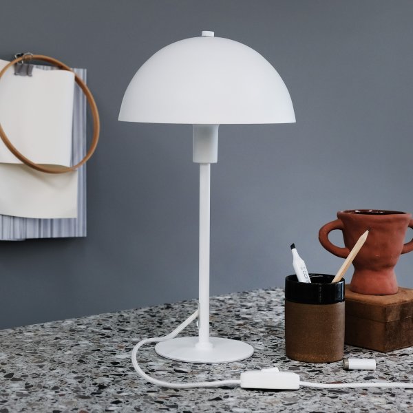 Stockholm 40cm Hvit bordlampe Fra Dyberg Larsen - Den lille hvite bordlampen i Stockholm-serien, med en høyde på 38 cm, er ideell for å gi lys i bokhyllen, på en smal hylle, vinduskarmen, nattbordet og mange andre steder.