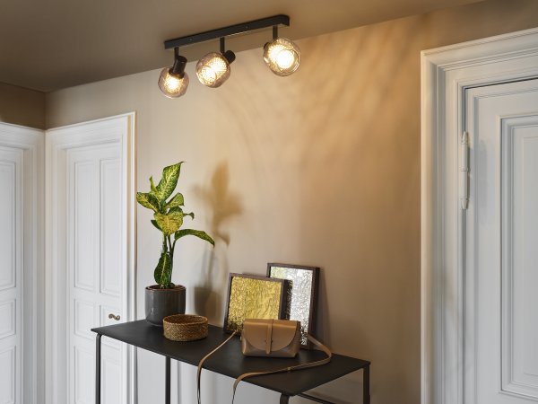 Firefly 3 Svart spotlight Fra Osram - De r&ouml;rliga spotlightsen med sk&auml;rmar av gr&aring;tonat glas i kombination med de guldiga detaljh&ouml;ljet som omfamnar ljusk&auml;llorna bidrar med en elegans till rummet.