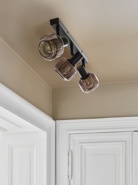 Firefly 3 Svart spotlight Fra Osram - De r&ouml;rliga spotlightsen med sk&auml;rmar av gr&aring;tonat glas i kombination med de guldiga detaljh&ouml;ljet som omfamnar ljusk&auml;llorna bidrar med en elegans till rummet.