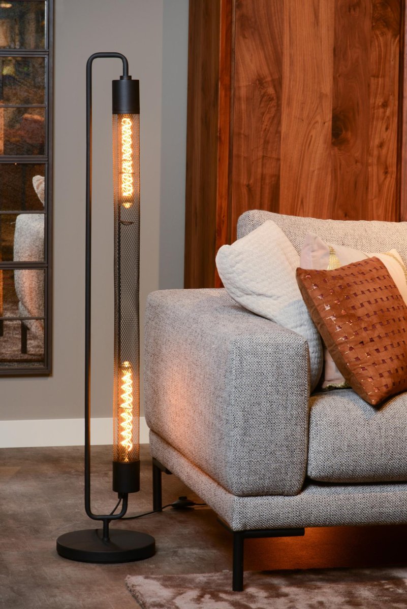 Calixt Svart gulvlampe Fra Lucide - Med sin rene og slanke design, og for eksempel to gl&oslash;delamper innelukket i en sylinder av nett og sitt metalliske utseende, passer den perfekt inn i et moderne interi&oslash;r.