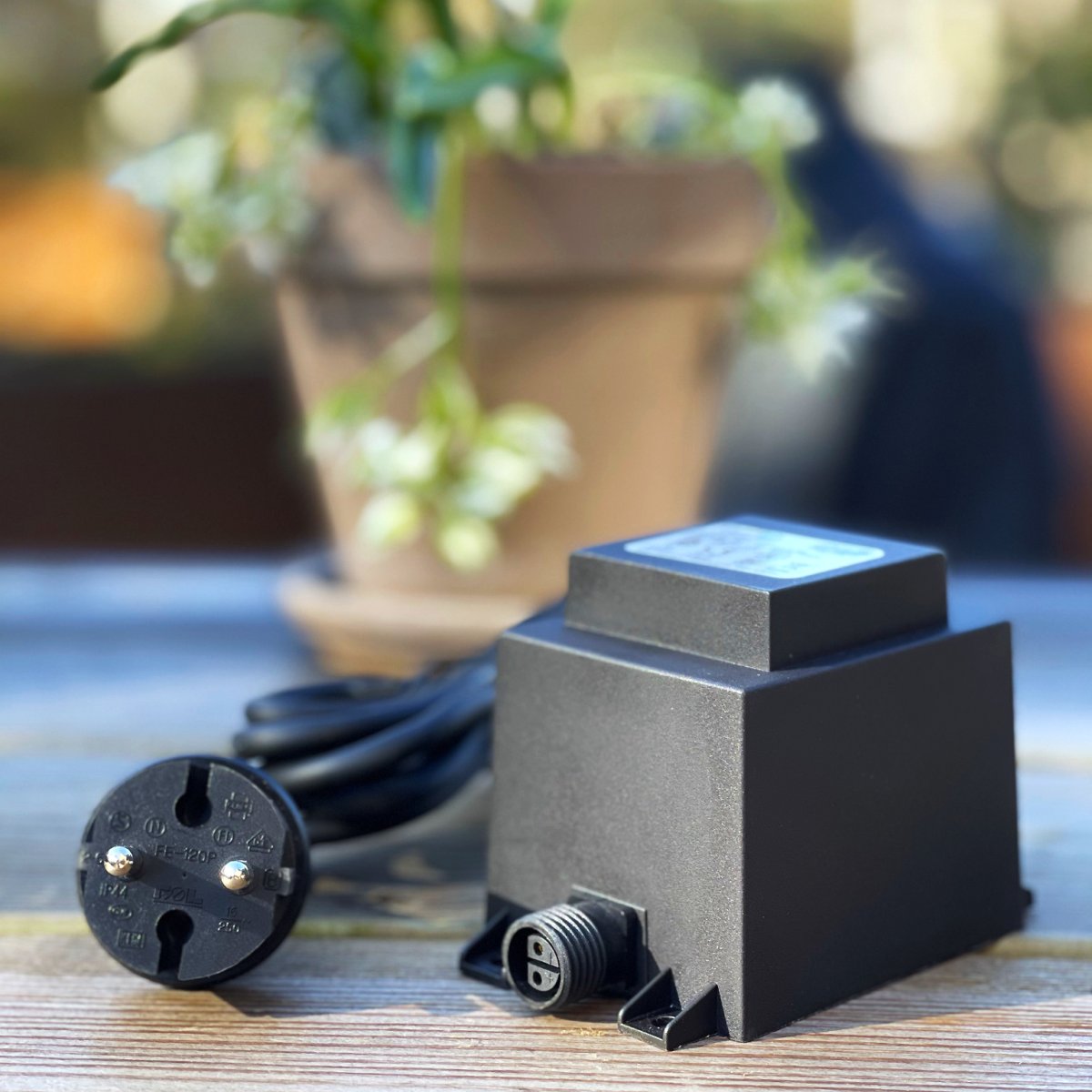 Transformator 60w Svart Fra Lightson - Transformatoren har en 12 volts hurtigkobling i den ene enden og en 2 meter lang ledning med støpsel i den andre, som du kobler til en vanlig stikkontakt.