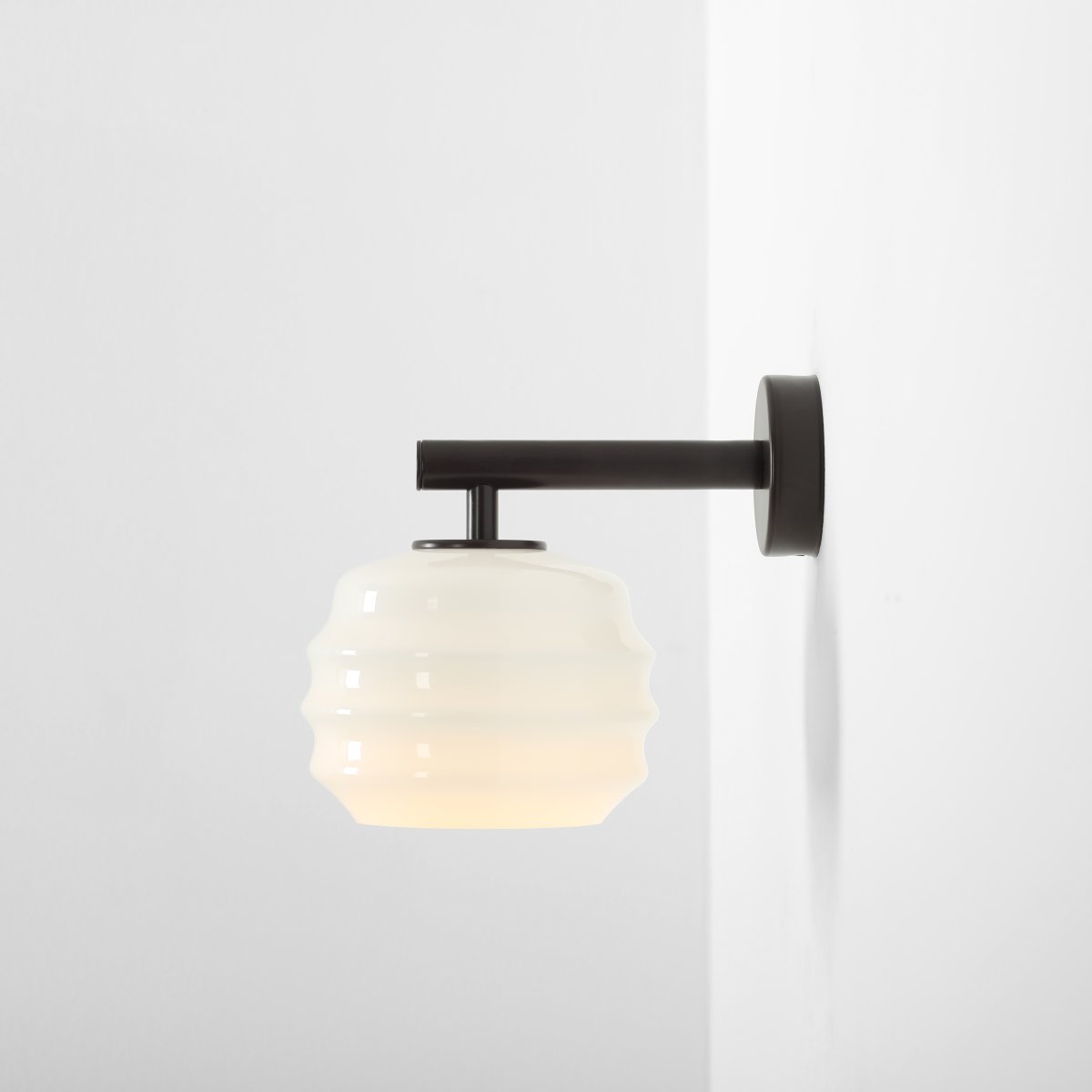 Puff 23cm Mørk brun vegglampe Fra Artera - Den dekorative skjermen i hvitt opalglass har en bølget form som gir lampen et lekent og elegant uttrykk.