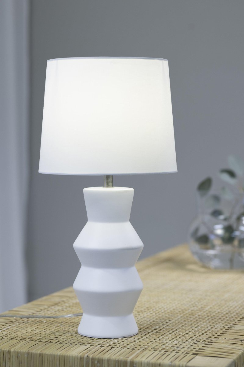 Sienna 46cm Hvit bordlampe Fra Markslöjd - Sienna bordlampe er en stilig hvit lampe med en vakker keramisk sokkel og en hvit tekstilskjerm som skaper et mykt lys.