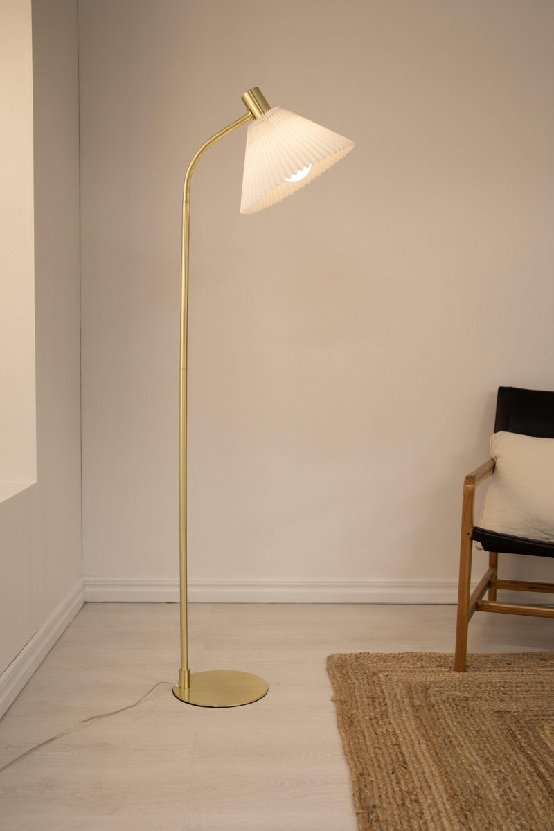 Mira Børstet messing gulvlampe Fra Markslöjd - Mira gulvlampen er 145 cm høy, har en lampefot i messingfarget metall og en plissert lampeskjerm i hvitt stoff.