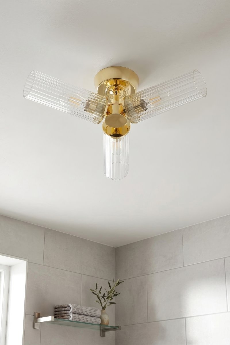 Rimini Ø40 Messing baderomslampe Fra Markslöjd - Rimini er en elegant taklampe som kombinerer en skinnende messingfinish med tre avlange skjermer i klart, riflet glass.