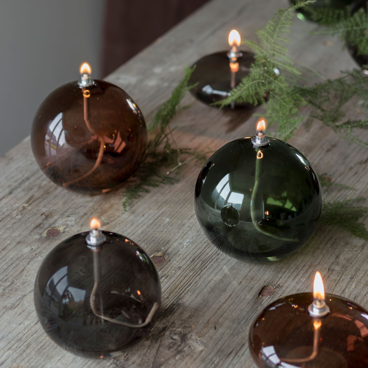 Oljelampa Aura Medium Røykfarget Fra Mette Ditmer - Dess eleganta design och r&ouml;kf&auml;rgade glas sprider ett mjukt, varmt ljus som ger en lugn och mysig k&auml;nsla.
