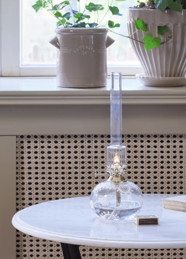 Kerosene lamp Oval Marja Gjennomsiktig Fra Strömshaga - En vakker rund parafinlampe i klart glass med vakre hvite h&aring;ndlagde blomster, messingbrenner og brennerr&oslash;r i klart glass.