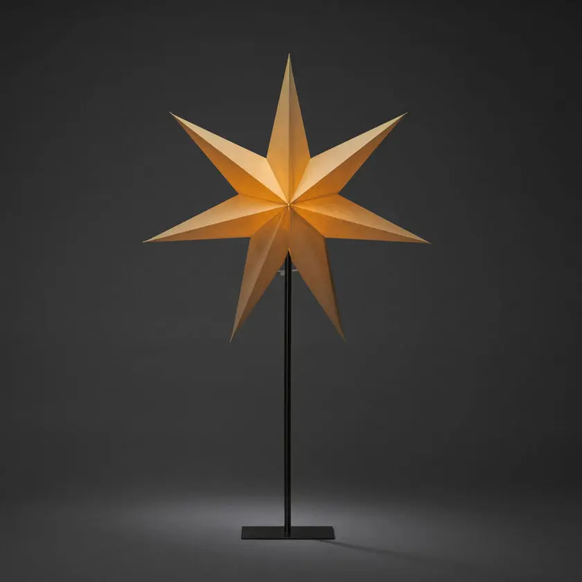 Papirstjerne Ø50 Beige Fra Konstsmide - Den stilige stjernen i beige farge hviler p&aring; en elegant svart metallinnstilling og sprer en myk, behagelig gl&oslash;d.