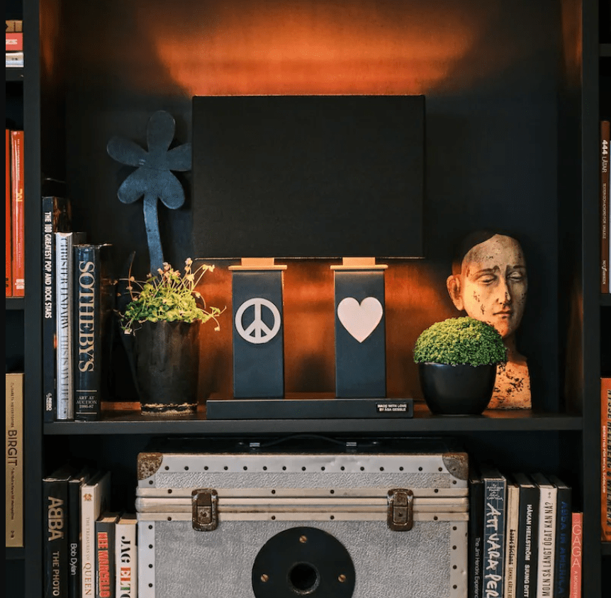 Stand By Me 50cm Svart bordlampe Fra By Rydéns - Den brede, sorte stofflampeskjermen harmonerer i kontrast med de smalere s&oslash;ylene p&aring; lampefoten, som begge er dekorert med et symbol i metall, fredsskiltet p&aring;; ett og ett hjerte p&aring; den andre.