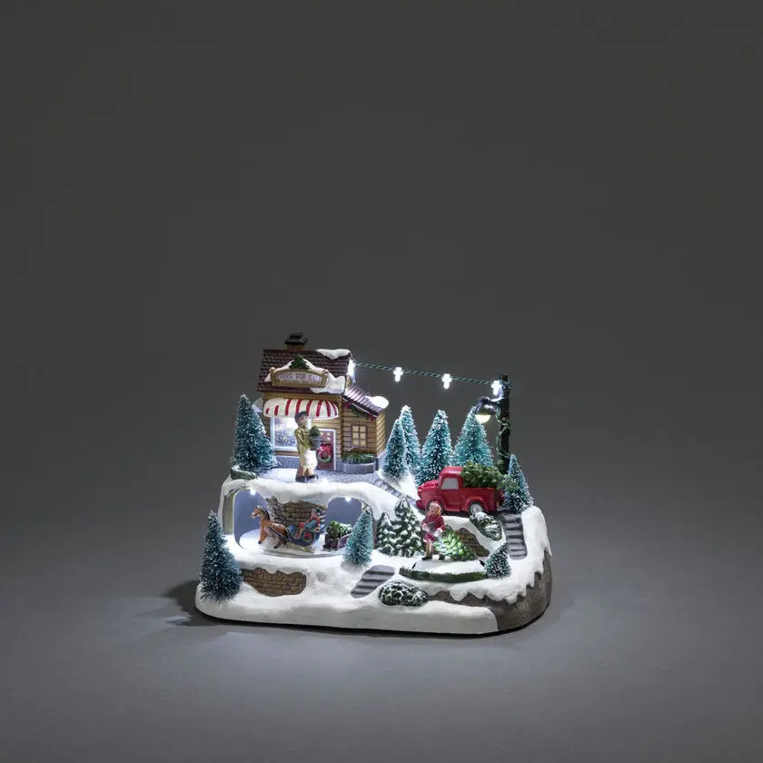 Mekanisk Juledekorasjon Med Juletresalg 17cm Flerfarget Fra Konstsmide - Skap en livlig julestemning med denne mekaniske juledekorasjonen &ndash; en sjarmerende scene med juletr&aelig;r i vinterdrakt.