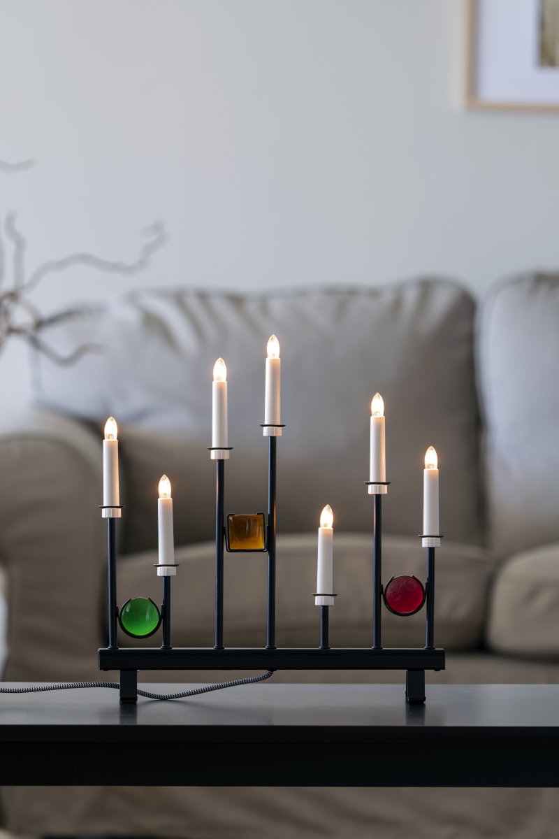 Candelabra 7 Lights Svart Fra Konstsmide - De syv lysene er innrammet av dekorative fargede glassdetaljer i gr&oslash;nt, r&oslash;dt og rav, som skaper en elegant og festlig atmosf&aelig;re.