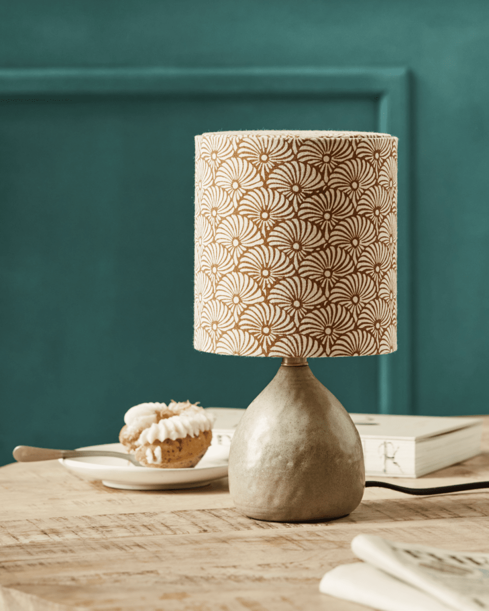 Flores 30cm Sand bordlampe Fra House Doctor - Den har en sandfarget keramisk base og en linlampeskjerm utsmykket med håndtrykte sand- og brune viftemotiver, som på en vakker måte balanserer en moderne og koselig estetikk.
