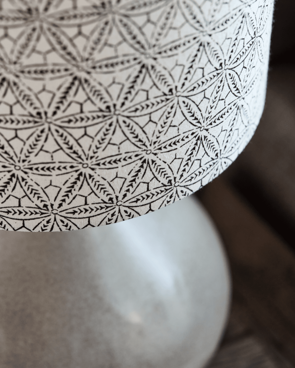 Florie 60cm Sand bordlampe Fra House Doctor - Den keramiske basen i en beroligende sandskygge gir et stabilt og elegant fundament, mens lampeskjermen i lin viser et håndtrykt svart etnisk mønster for en unik og kunstnerisk følelse.