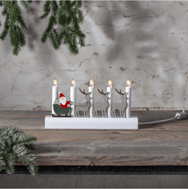 Julia Hvit Fra Star Trading - Adventslysestake dekorert med julenissen og reinsdyrene hans malt i julefarger.