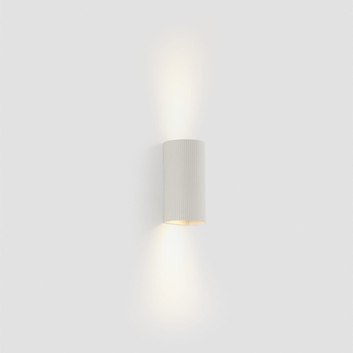 Sole 15cm Hvit rillet vegglampe Fra Faro Barcelona - Den er tilgjengelig i to st&oslash;rrelser og kan avgi lys i &eacute;n eller to retninger, noe som gj&oslash;r den ideell for ganger og mindre rom.