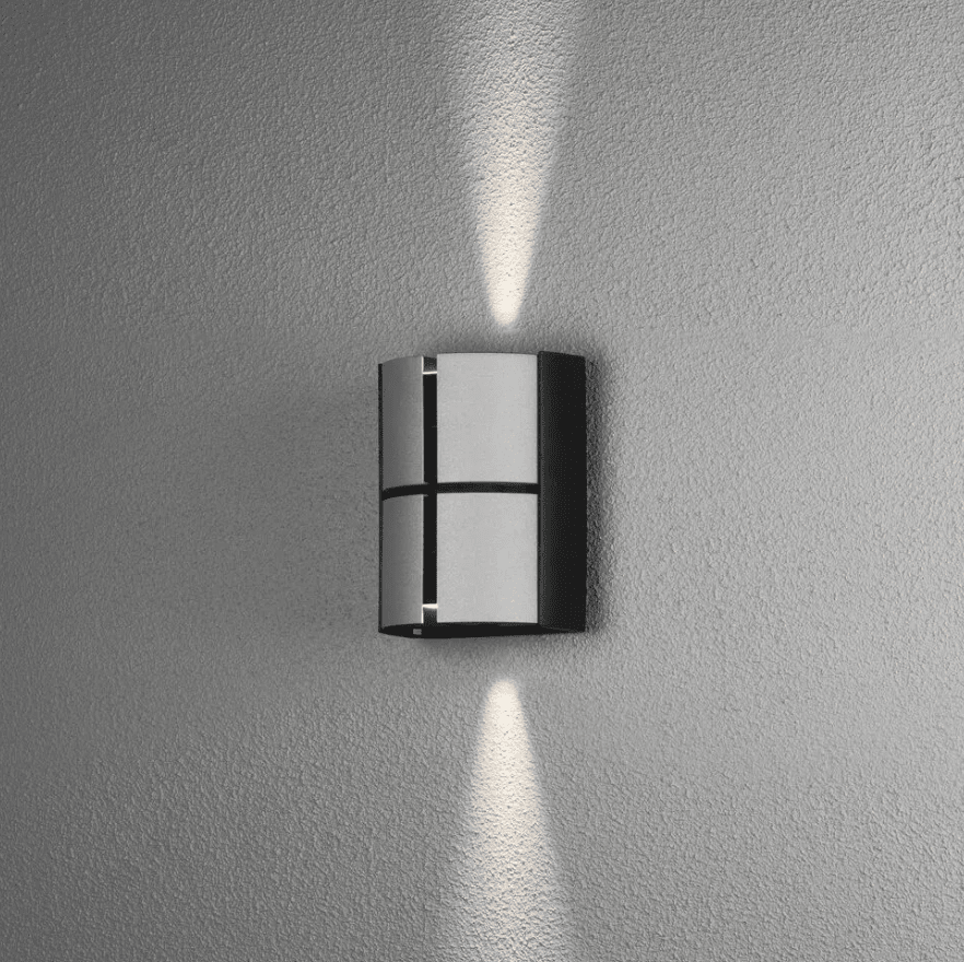 Vidar 15cm Sølv utendørslampe Fra Konstsmide - Lampen lyser opp og ned på veggen og tilbyr justering av lysstrålen slik at du kan justere spredningsgraden du ønsker.