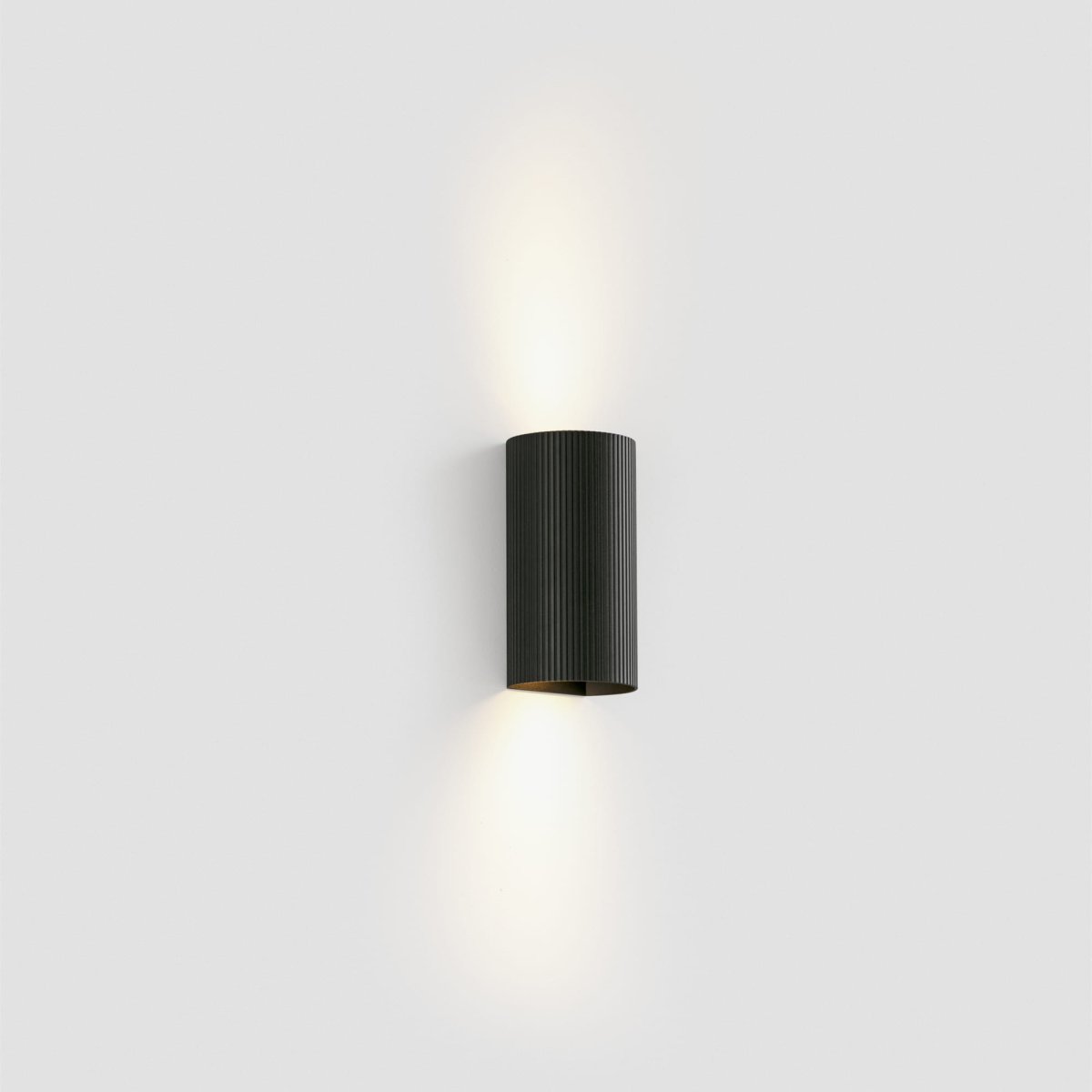 Sole 15cm Svart rillet vegglampe Fra Faro Barcelona - Den er tilgjengelig i to st&oslash;rrelser og kan avgi lys i &eacute;n eller to retninger, noe som gj&oslash;r den ideell for ganger og mindre rom.