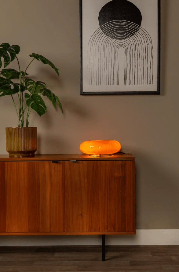 Sentino 10cm Oransje bordlampe Fra Lucide - Denne unike bordlampen kombinerer et blankt lakkert glasshus i smultringform med en elegant metallbase – et stiluttrykk som både tiltrekker seg oppmerksomhet og løfter helhetsinntrykket i rommet.