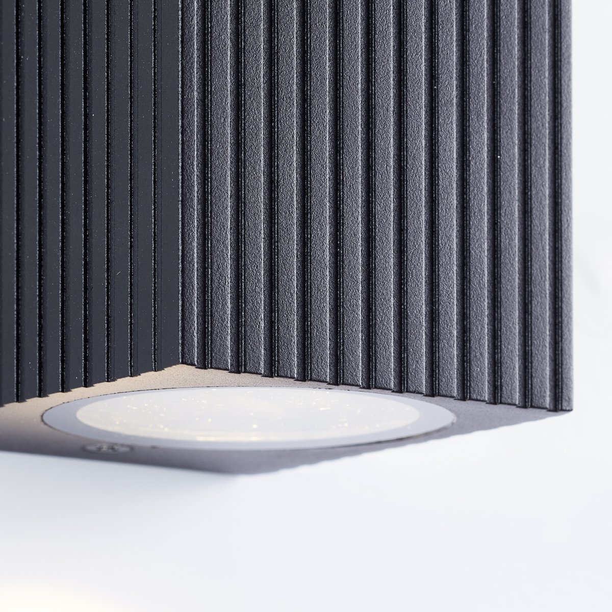 Jelani Svart utendørslampe Fra Brilliant - Lampen er designet for å spre et fokusert lys nedover, noe som skaper en vakker lyseffekt på veggen og bidrar til både trygghet og atmosfære i utendørsmiljøer.