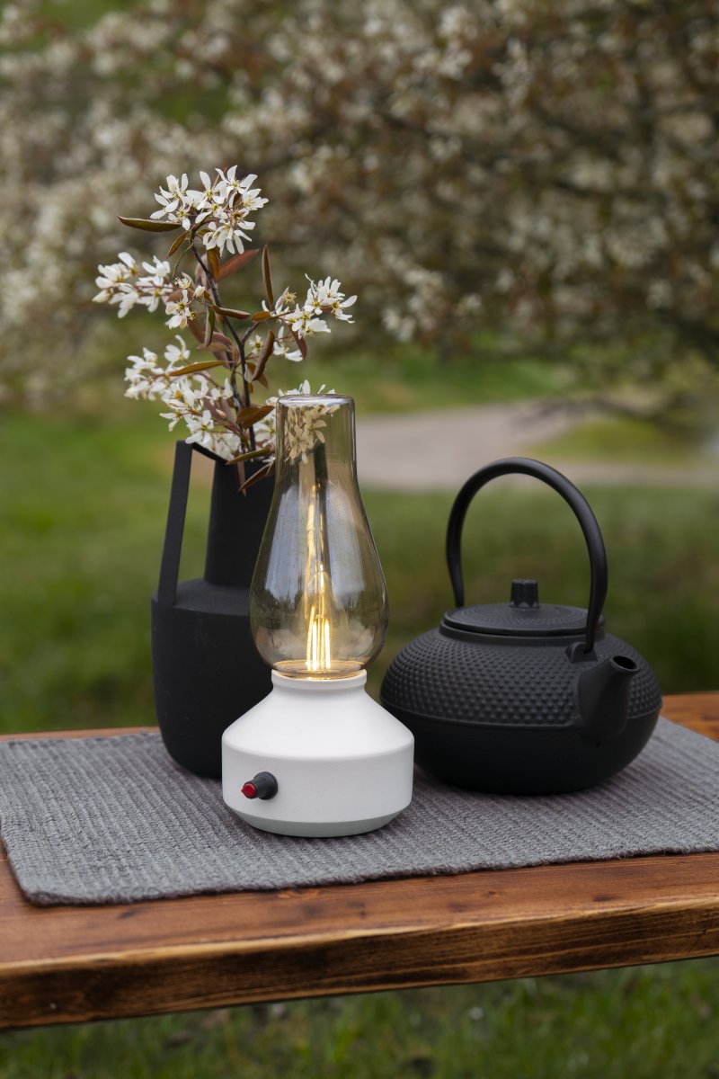 Oppladbar bordlampe 25cm Hvit bærbar Fra Konstsmide - Lampen er laget av metall og glass med en hvit lampefot og en praktisk dimmer som gjør det enkelt å justere det varmhvite, atmosfæriske lyset.