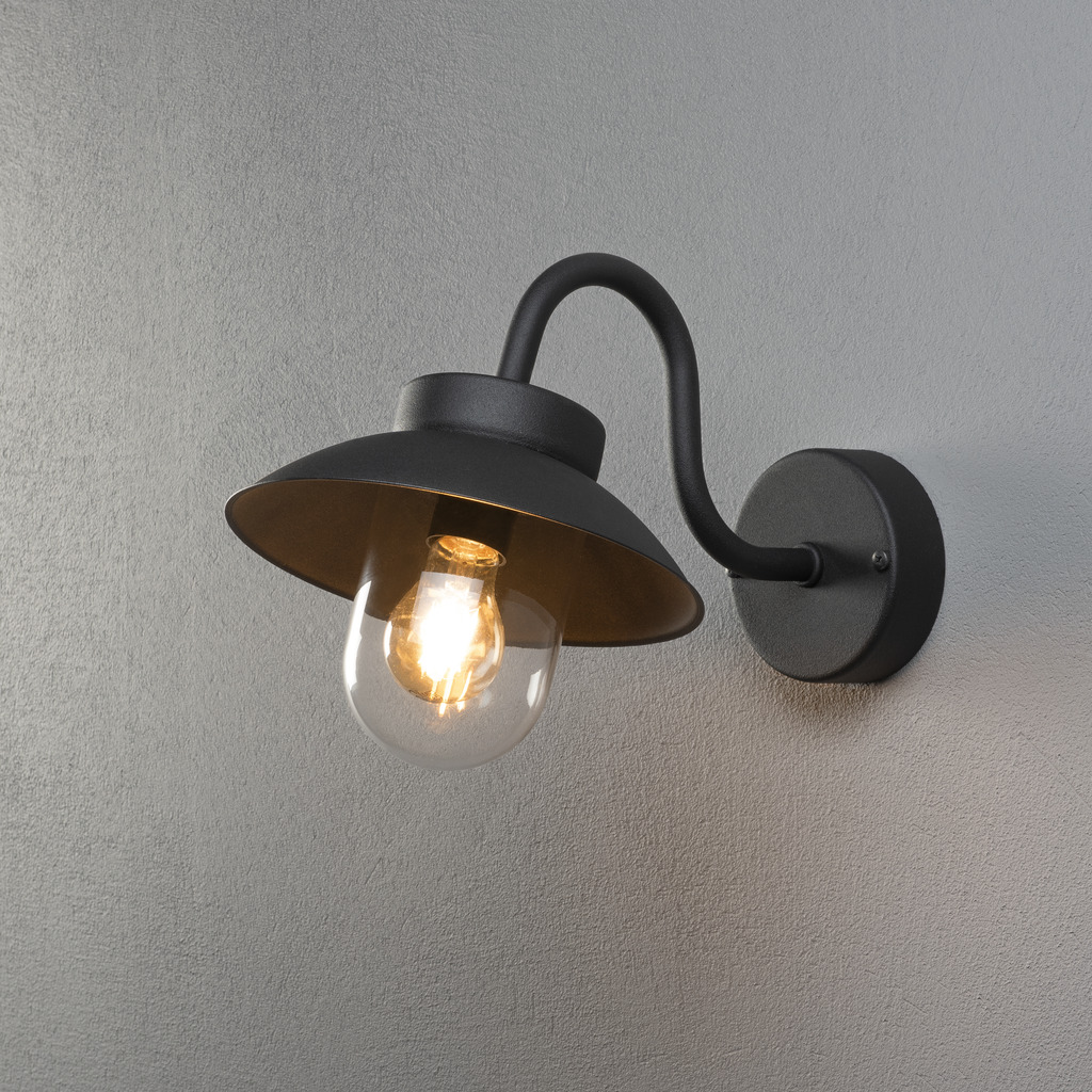Vega Svart utendørslampe Fra Konstsmide - Den brede skjermen og den klare glasskuppelen sprer et behagelig og rettet lys, noe som gjør lampen perfekt for entre og uteplasser.