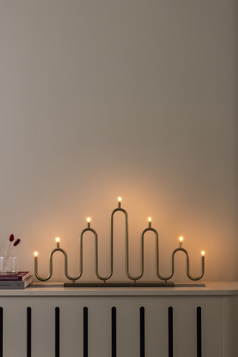 Noel 7 Messing Fra Globen Lighting - Det myke, bølgete designet er laget av metallrør som er bøyd for hånd på forskjellige nivåer og gir en moderne tolkning av den klassiske adventslysestaken.