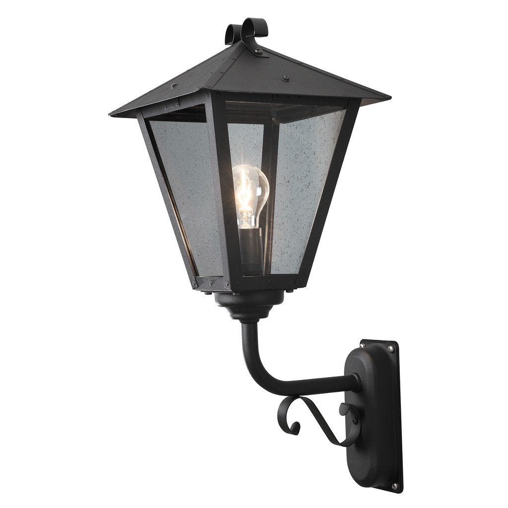 Benu Svart utendørslampe Fra Konstsmide - Lampens klassiske lyktform og robuste materiale gj&oslash;r den til et perfekt valg for de som &oslash;nsker &aring; skape en innbydende atmosf&aelig;re ved innganger eller lange korridorer.