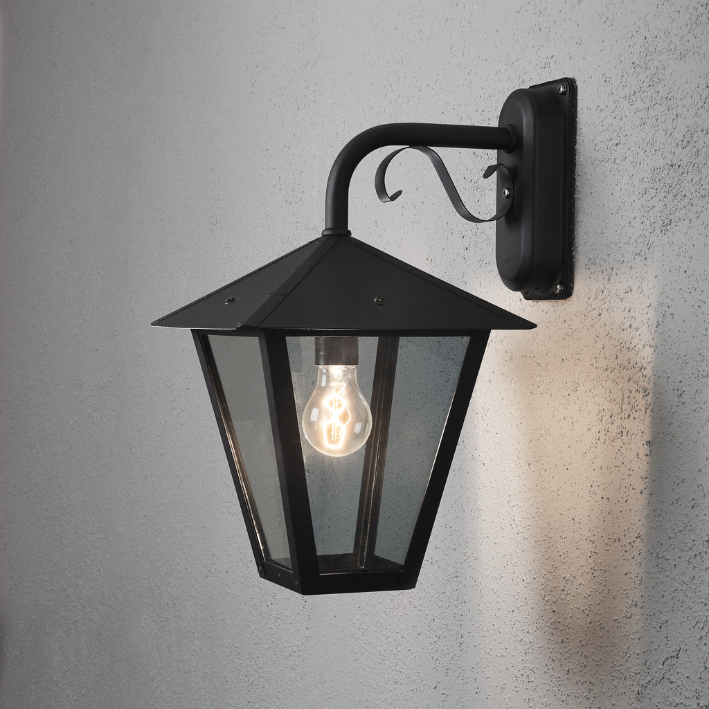 Benu Svart utendørslampe Fra Konstsmide - Lampens klassiske lyktform og robuste materiale gj&oslash;r den til et perfekt valg for de som &oslash;nsker &aring; skape en innbydende atmosf&aelig;re ved innganger eller lange korridorer.