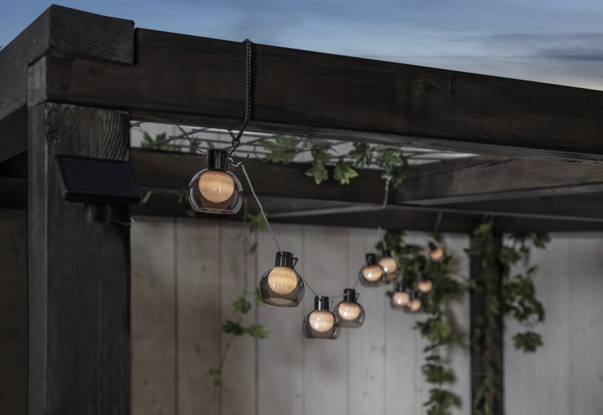 Smoky Gjennomsiktig solcellelampe Fra Star Trading - Soldrevet lysstreng med 10 vakre røykfargede pærer som har en indre opalpære som skinner med en varm hvit glød.