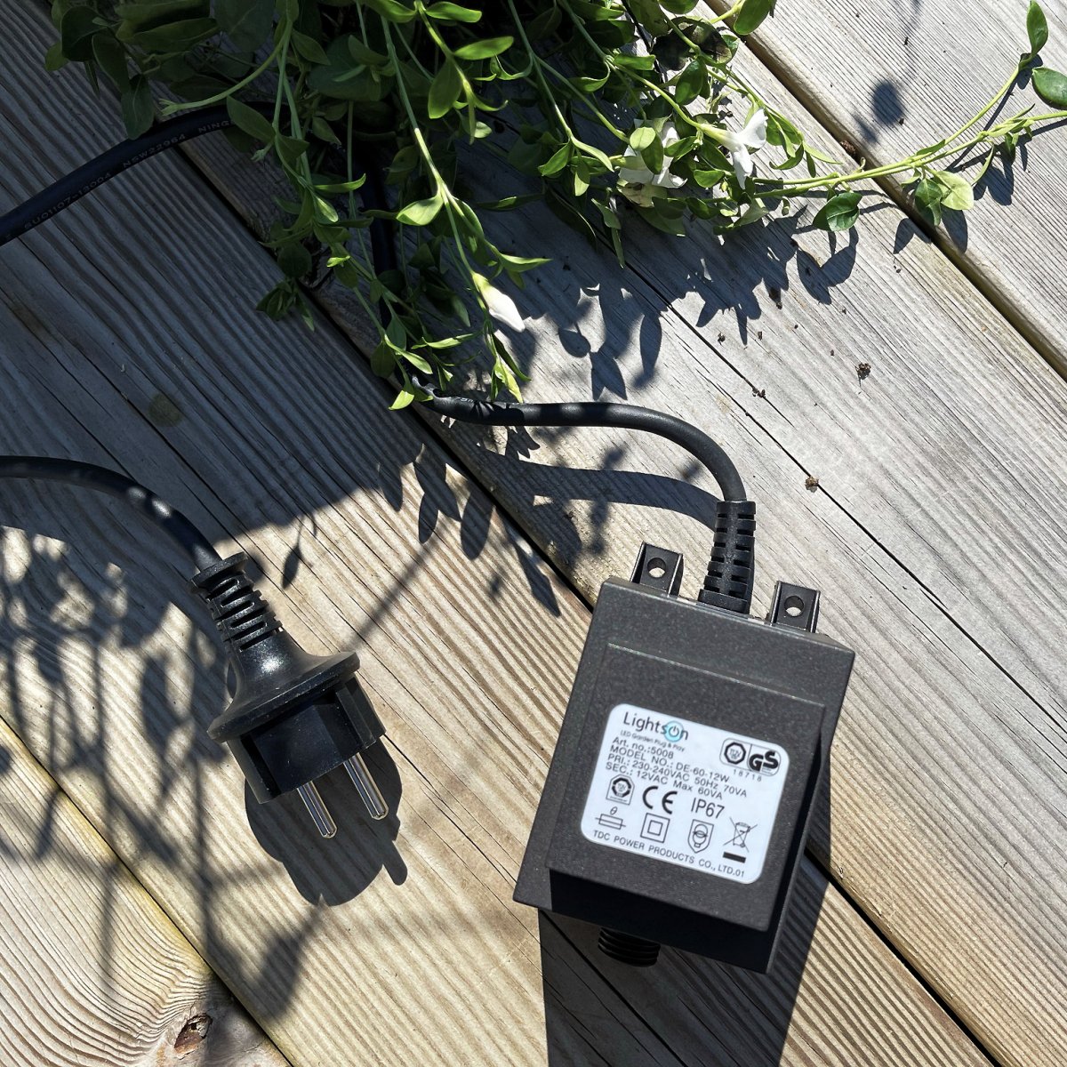 Transformator 60w Svart Fra Lightson - Transformatoren har en 12 volts hurtigkobling i den ene enden og en 2 meter lang ledning med støpsel i den andre, som du kobler til en vanlig stikkontakt.