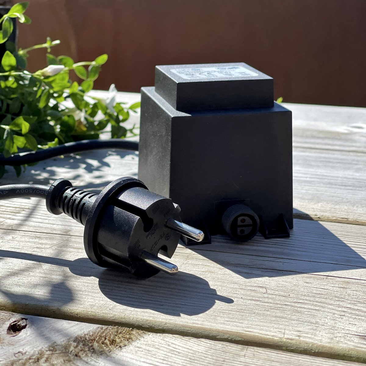 Transformator 105w Svart Fra Lightson - Transformatoren har en 12 volts hurtigkobling i den ene enden og en 2 meter lang ledning med støpsel i den andre, som du kobler til en vanlig stikkontakt.