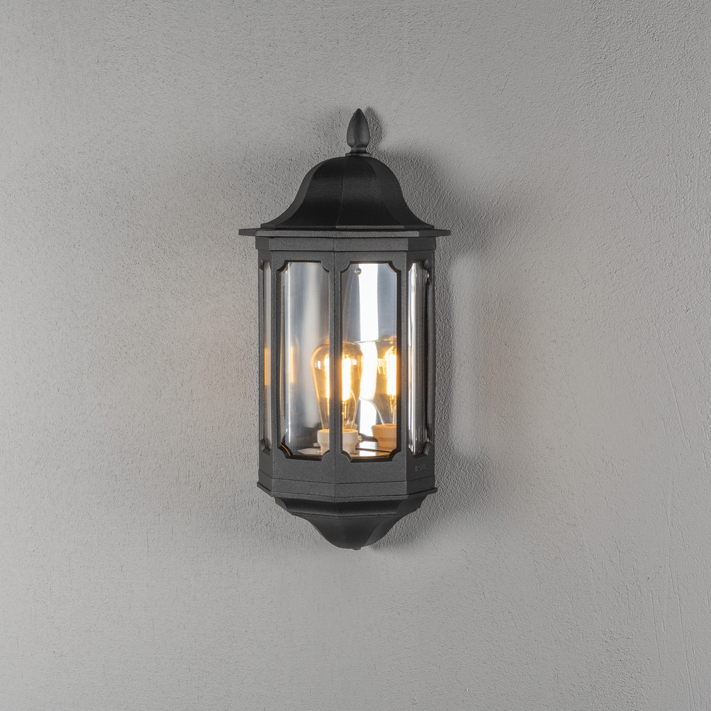 Pallas Svart utendørslampe Fra Konstsmide - Med sitt myke lys skaper den en innbydende atmosfære som er perfekt for innganger og uteplasser.