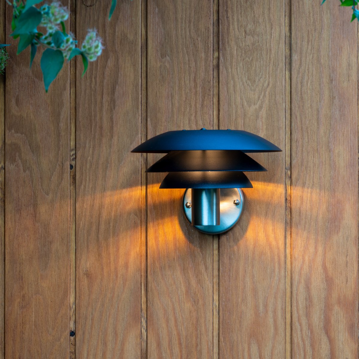 DL20 Rustfritt stål utendørslampe Fra Dyberg Larsen - Lampen har tre ikoniske skjermer i forskjellige størrelser som sprer et magisk lys og er laget av rustfritt stål med elegante matte sorte skjermer.