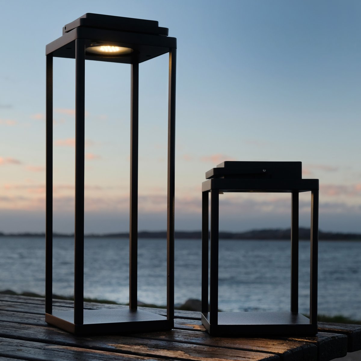 Lucca 24cm Svart bærbar Fra Dyberg Larsen - Lucca-lykten er laget av robust metall med bærehåndtak og innebygd LED på toppen, perfekt som dekorasjon på terrassen, balkongen eller ved inngangsdøren.