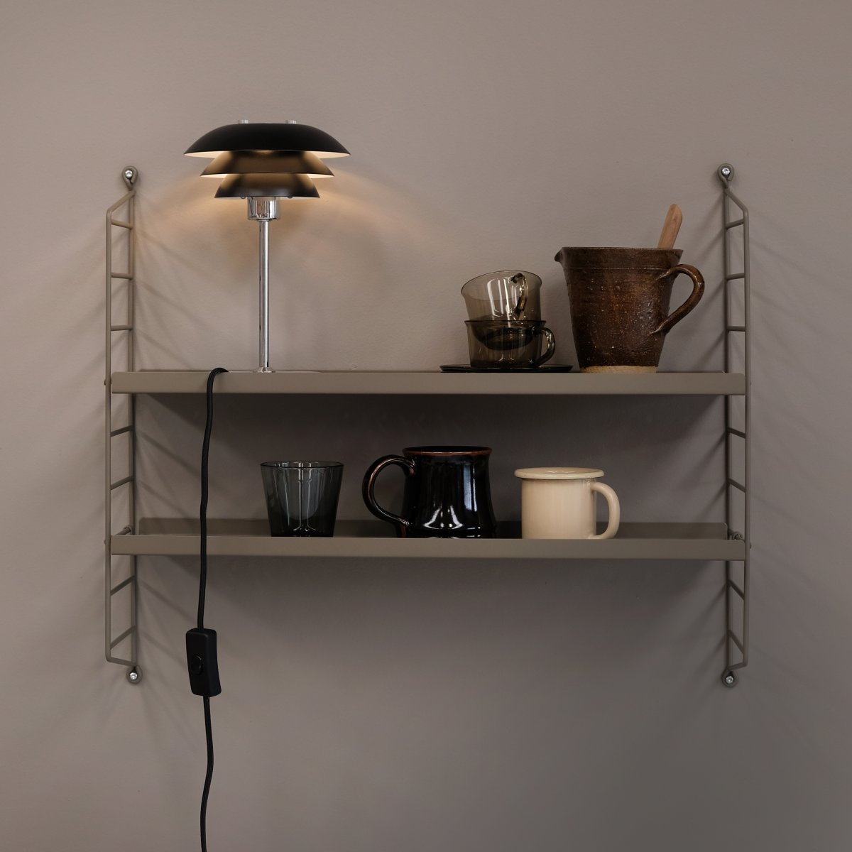 DL16 25cm Svart bordlampe Fra Dyberg Larsen - Skjermene er laget av metall og basen i krom, med fargealternativene sort og hvit.