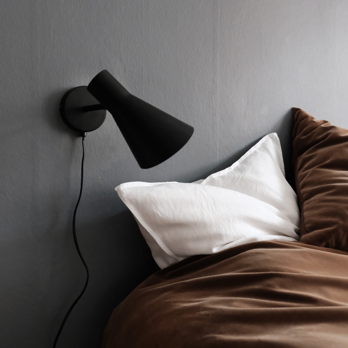 DL12 Svart leselampe Fra Dyberg Larsen - Med sin moderne, matt sorte design og vinklede skjerm gir DL12 et fokusert og behagelig lys, ideelt for studier eller som nattbordslampe.