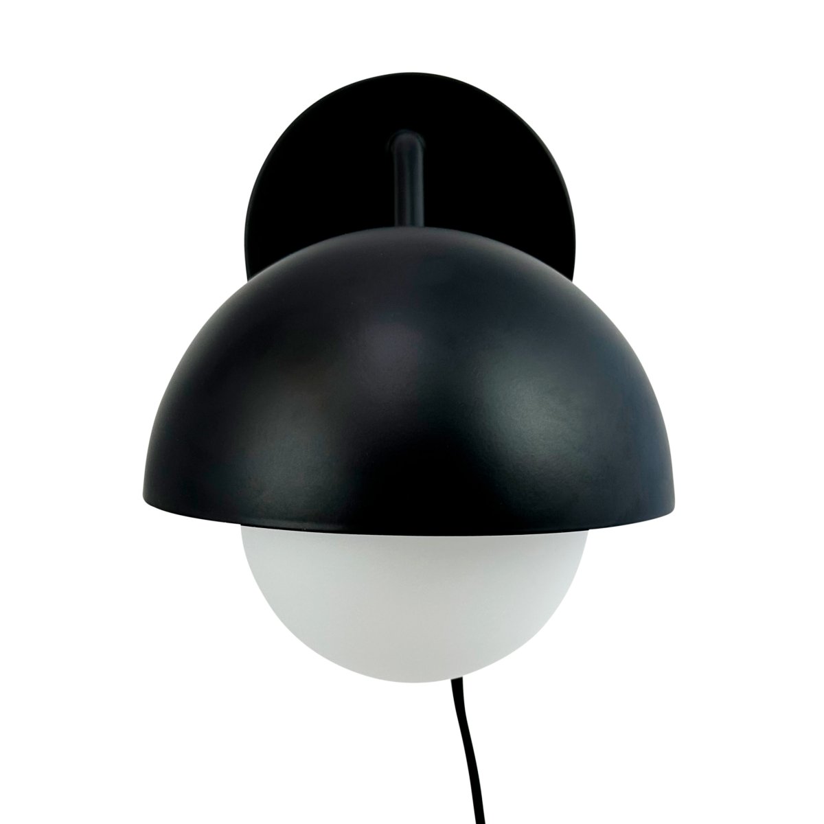 Rose Ø15 Matt svart vegglampe Fra Dyberg Larsen - Glasskuppelen fungerer som en naturlig lysspreder og skaper en varm og innbydende atmosfære i rommet.