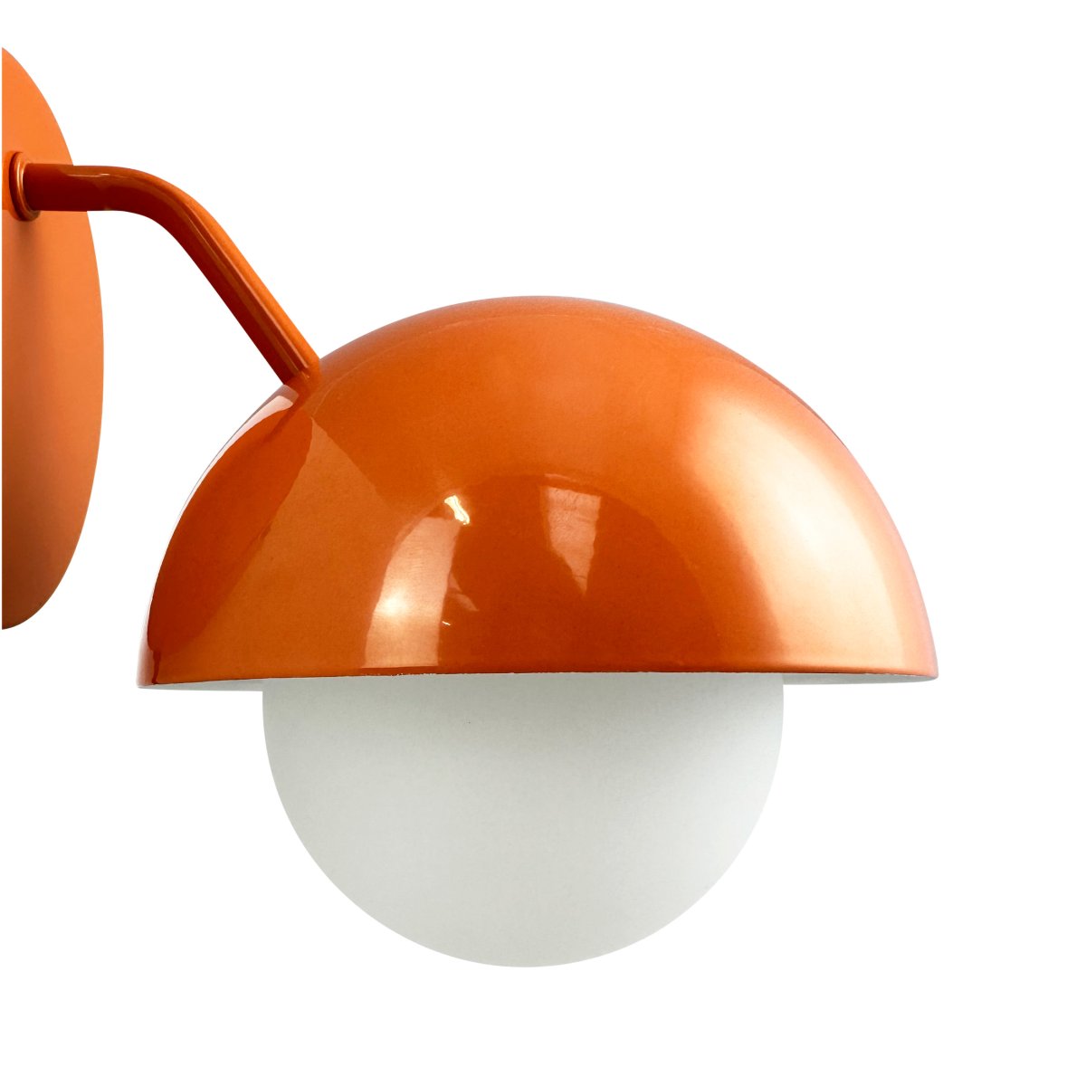 Rose Ø15 skinnende oransje vegglampe Fra Dyberg Larsen - Glasskuppelen fungerer som en naturlig lysspreder og skaper en varm og innbydende atmosfære i rommet.
