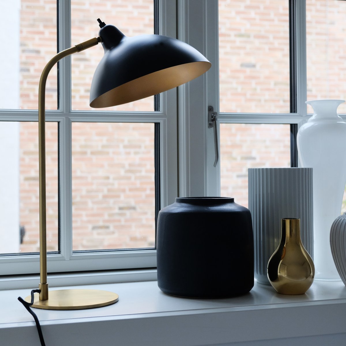 Futura 55cm Messing bordlampe Fra Dyberg Larsen - Den svarte overflaten og den antikkfargede innsiden av skjermen sprer et varmt lys og skaper en koselig atmosf&aelig;re i hjemmet.