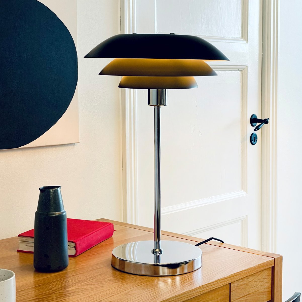 DL31 50cm Svart bordlampe Fra Dyberg Larsen - Bordlampen er klassisk og dramatisk i sort i kombinasjon med forkrommet metall, perfekt til et m&oslash;rkt hj&oslash;rne av hjemmet, i vinduet eller som en elegant interi&oslash;rdetalj i seg selv.