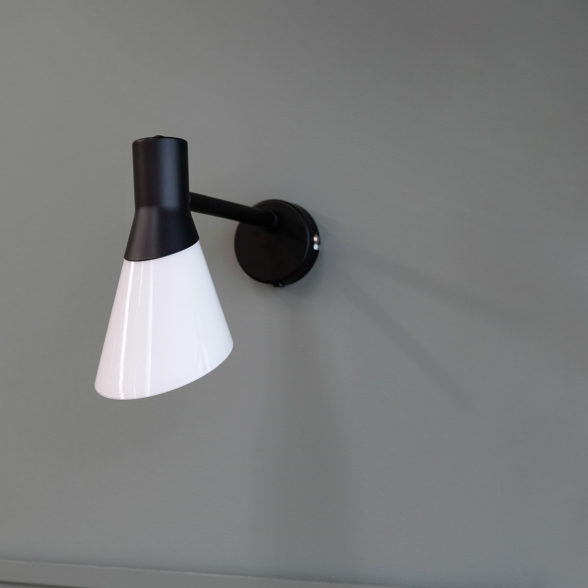 Gent 30cm Svart vegglampe Fra Dyberg Larsen - Gent er en moderne og stilig vegglampe med lampeskjerm laget av opalt glass i kombinasjon med sort metall.
