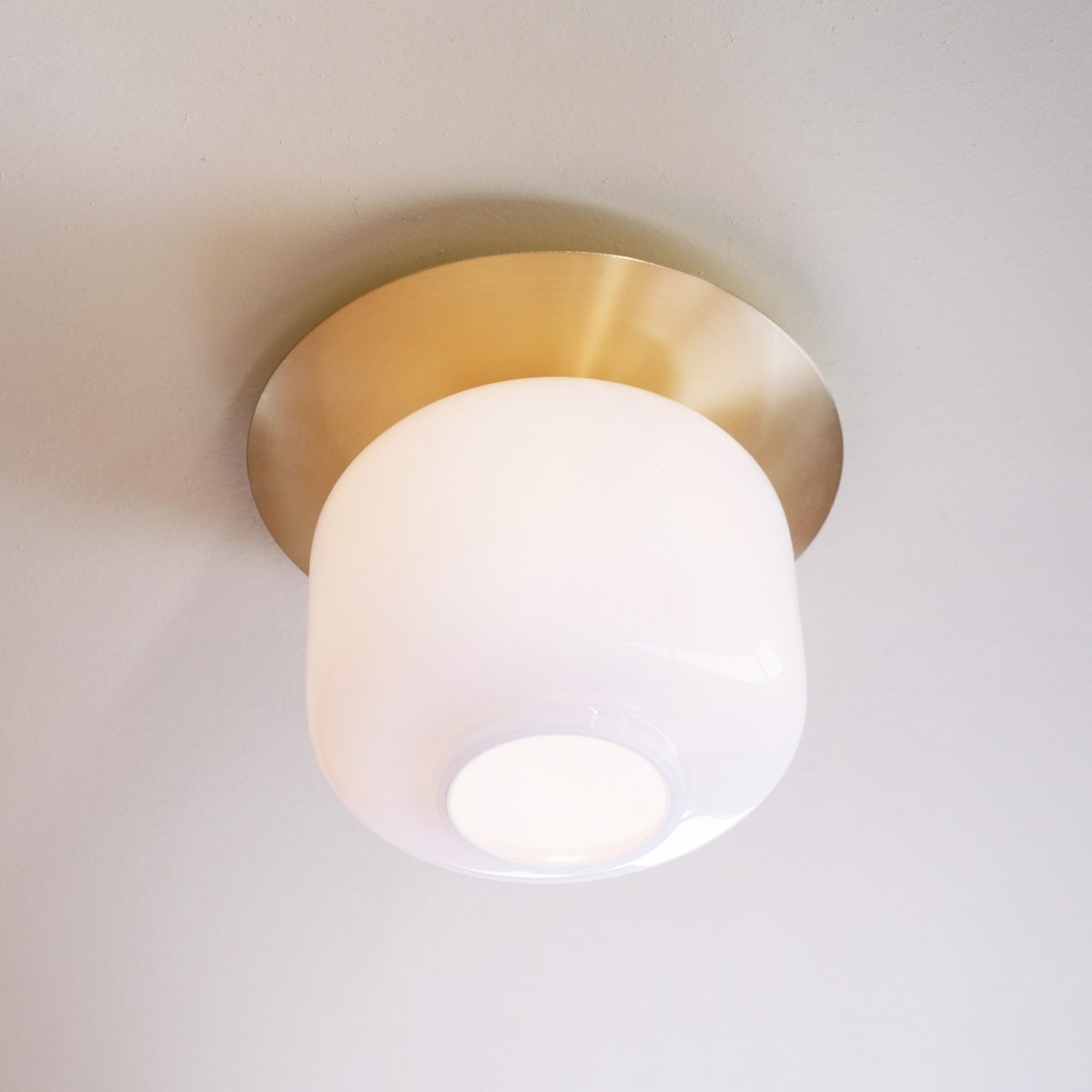 Arp Ø25 Messing plafond Fra Dyberg Larsen - Lampen sitter tett inntil taket og den messingfargede platen skaper en elegant barriere mellom taket og glasset.