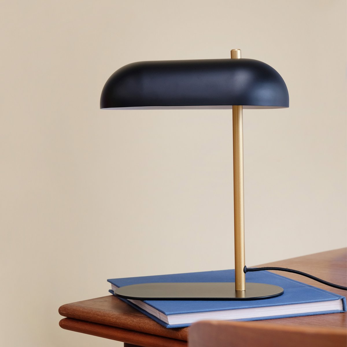 Arch 36cm Messing bordlampe Fra Dyberg Larsen - Laget av matt svart metall og utstyrt med en messingarm, gir den hjemmet ditt et tidløst preg av klassisk moderne design.