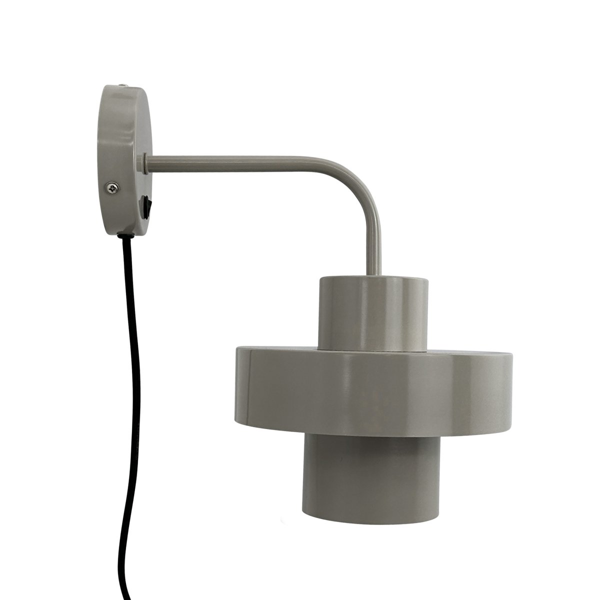 Stoke Ø15 Varm grå vegglampe Fra Dyberg Larsen - Den er laget av metall med en blank overflate som fremhever de sylindriske formene på lampen og skaper en balansert kontrast med andre materialer som stein, tre.