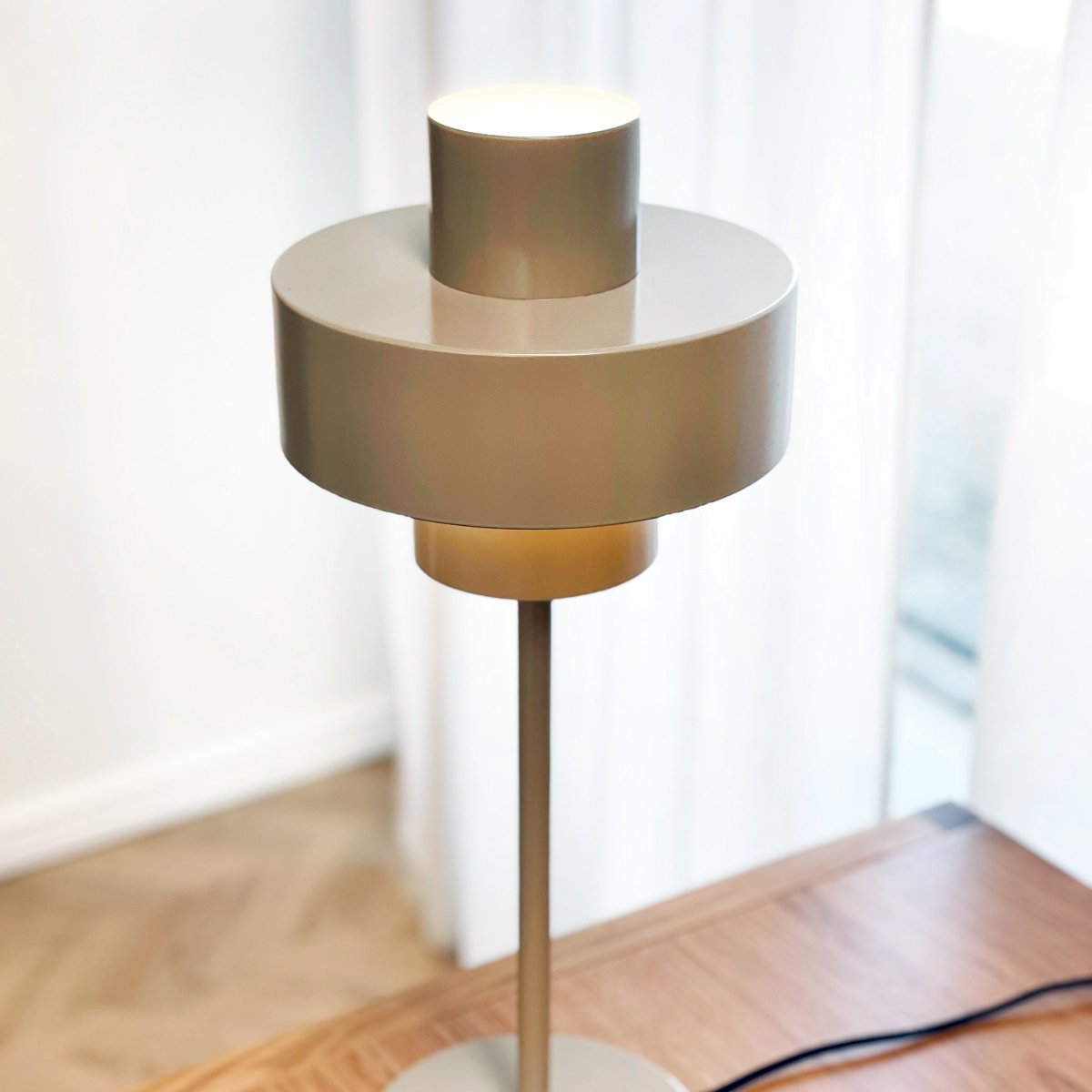Stoke 50cm Varm grå bordlampe Fra Dyberg Larsen - Lampen passer perfekt som både en skulpturell interiørdetalj og lyspunkt, for eksempel på kjøkkenet, på skrivebordet eller i stuen.